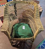 Front view of antique painted wicker armchair showing lattice-style back and arms, green cushion on seat, and overall condition.