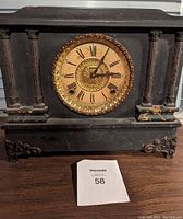 Front view of antique mantel clock showing carved wooden case, Roman numeral dial, and decorative bezel