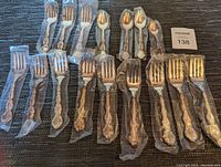 All forks and spoons sealed in original plastic, laid out on a table showing quantity and packaging condition.