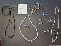 Full lot view showing pearl and hematite necklaces, earrings, and bracelets spread on surface.