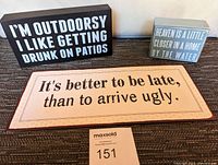 Three decorative signs placed on a carpeted floor, showing all text clearly