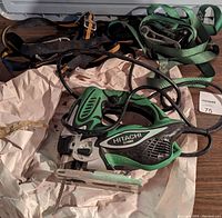 Hitachi CJ110MV jig saw with variable speed and ergonomic features visible. Multiple tie-down straps including green and black ones are displayed beside it.