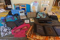 Full view of ladies accessory lot on tabletop showing wallets, readers, hair towel, heel protectors, knee sleeve, and tights.