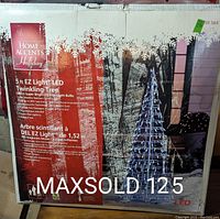 Photo of box front showing 5 ft EZ Light LED Twinkling Tree by Home Accents Holiday with 280 blue lights and product details.