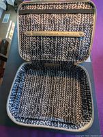 Open interior view of the Stella and Dot jewelry case showing patterned fabric lining, zippered pocket and elastic strap with button snaps.