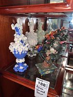 Two relief vases and one cloisonné bonsai arrangement displayed on a glass shelf