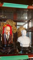 Red and beige display shelf with Lenin nesting doll and white bust in front of wood carving