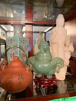 Three items displayed together on shelf: cloisonné vase, teapot, censer, figurine
