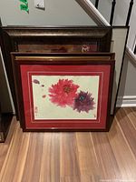 Four framed prints leaning against wall, displaying floral and nautical themes