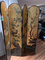 Four-panel screen displayed partially folded showing interior gold leaf panels with carved floral and bird scenes