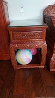 Side view of the wooden side table showing carved legs and open bottom shelf with toys stored inside.