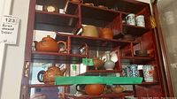 Overall view of wooden shelf displaying all miniature teapots, vases and clock