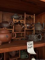 Full view of wooden display stand holding eight clay teapots