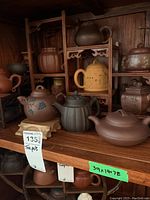 Front view of multiple clay teapots on wooden multi-tier display stand