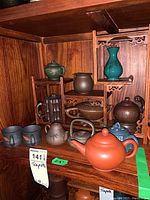 Full view of wooden stand with multiple teapots and cups arranged