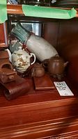 Group shot of all items showing three teapots, boat figurine, holder