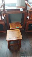 Wood side table with two wooden stools in front, showing full set and relative size.