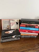 Photo showing two stacks of books with various titles visible including Vintage Tea Party, A Touch of Grace, The Swan Book, My Life as a Fake, Thirteen Reasons Why, The Fault in Our Stars, Me Before You, A.D. New Orleans after the Deluge, and Enough Already.