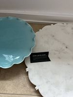 Photo showing the top surfaces of the blue ceramic and white marble cake stands, with a label visible on the marble stand.