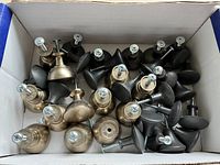 Box containing a mixture of gold and black cabinet knobs, visible variety in shapes and finishes with screws attached.