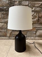 Front angle view of the Pottery Barn table lamp showing black matte base and white lampshade.
