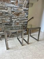 Three nesting tables displayed side by side against a stone wall