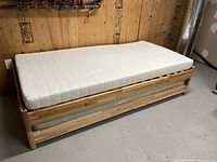 Full view of assembled pine bed frame with mattress