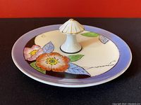 Top side view showing floral pattern and mushroom-shaped central handle with gold accents on ceramic dish.