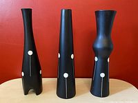 Front view of three black modern vases with white atomic dot line design, showing varying shapes