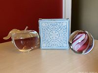 Three glass paperweights side by side with original Avon box in background