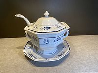Front view of the hand painted ironstone soup terrine with lid, ladle, and underplate, showing blue floral and decorative designs on white ceramic.