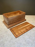 Open box showing dovetail joints, removable lid, and interior of cherry wood box with molding base.