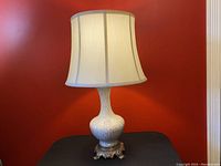 Full view of the lamp showing the cream fabric shade, art glass base with gold flecks, and brass ornate base.