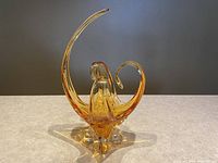 Front view of amber hand blown glass bowl with a tall spike and curled accents on sides showing overall shape and design.