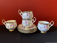 Four Stratford teacups with floral patterns arranged with four matching saucers, showing the set from various angles.