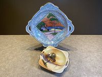 Both Noritake bowls shown with their hand painted landscape designs on a neutral surface.