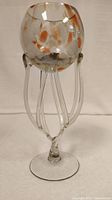 Side view showing the round bowl with tinted spots and clear glass elongated legs forming the base.