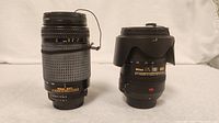 Front view of Nikon Nikkor AF 70-300mm lens (left) and Nikon Nikkor AF-S 18-200mm VR lens (right) on white background.