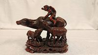 Front view of the resin Year of the Ox figurine showing the ox with a rider and two calves standing beneath.