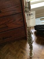 Full view of silver metal clarinet standing upright showing overall length and parts.