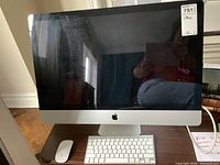 Front view of Apple iMac with keyboard and Magic Mouse on table