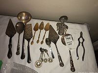 Full lot overview showing all serving utensils including pie servers, nutcracker, spoons, ladle and measuring spoons