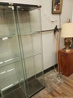 Glass showcase cabinet front and side showing glass doors, black top and bottom base, locking mechanism on door.