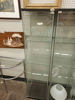 Full view of the glass showcase cabinet, showing front door with lock and shelves inside.