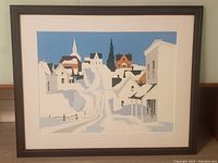 Framed serigraph print showing stylized winter village scene with snow and blue sky.