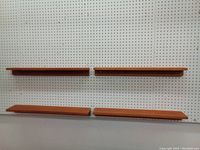 Front view of all four teak wall shelves mounted on white pegboard