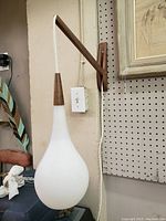 Wall-mounted teardrop frosted glass shade hanging from wood bracket.