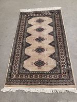 Full top view of the rectangular beige rug showing geometric medallions and decorative border with floral patterns.