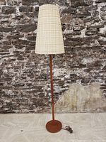 Full view of floor lamp showing base, pole, and shade against backdrop