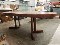 Side view of oval table showing twin T-shaped pedestal bases